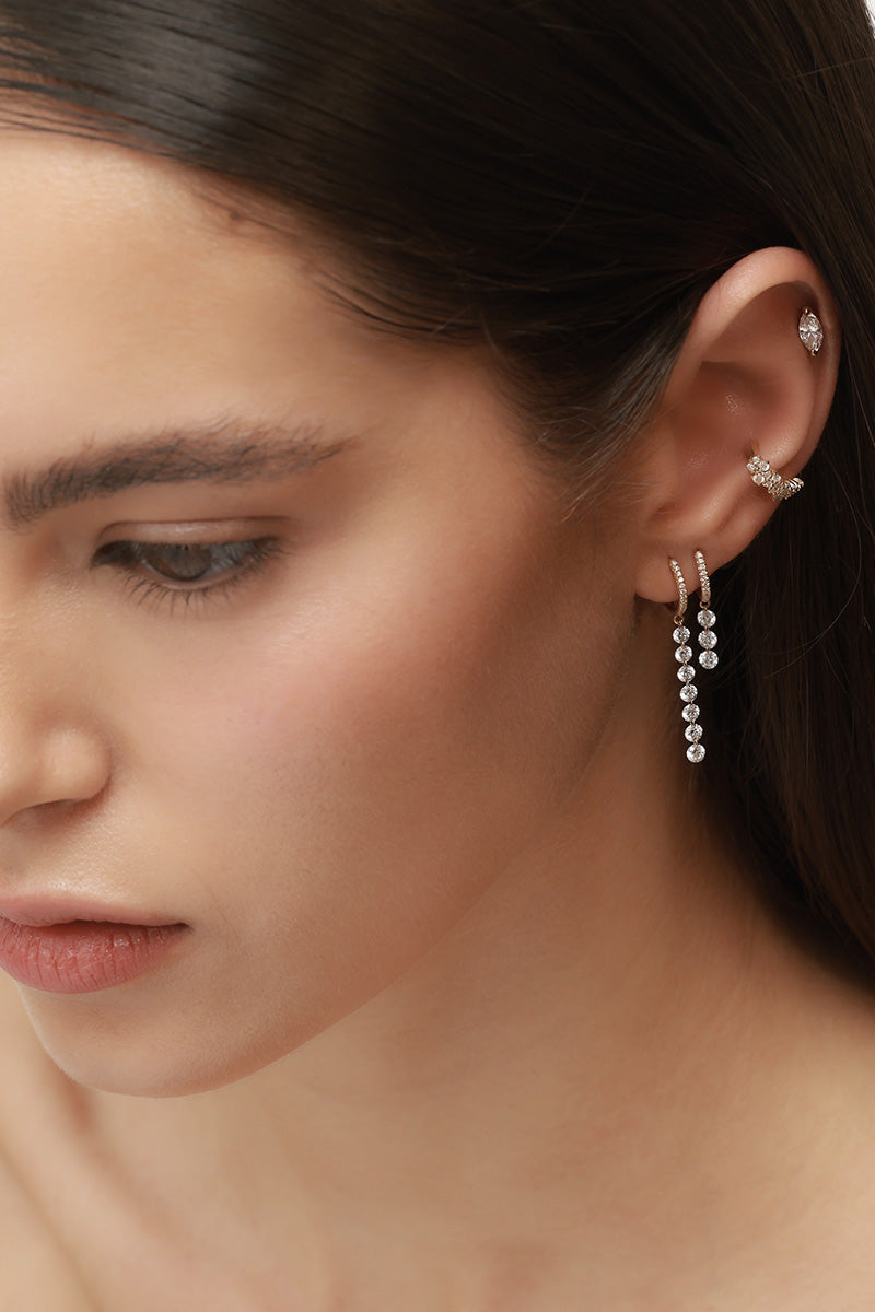 אישה עם עגילי יהלומים מזהב באוזן, כולל עגיל חישוק עם יהלומים נופלים, עגיל פירסינג משובץ ו Ear Cuff משובץ יהלומים, במראה נקי ומדויק