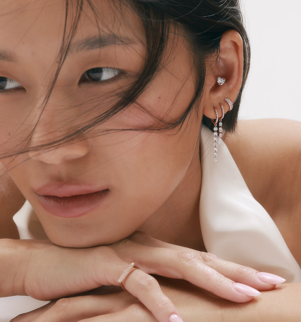 0.55ct heart-shaped lab-grown diamond piercing earring styled with multiple earrings and a diamond pinky ring on model