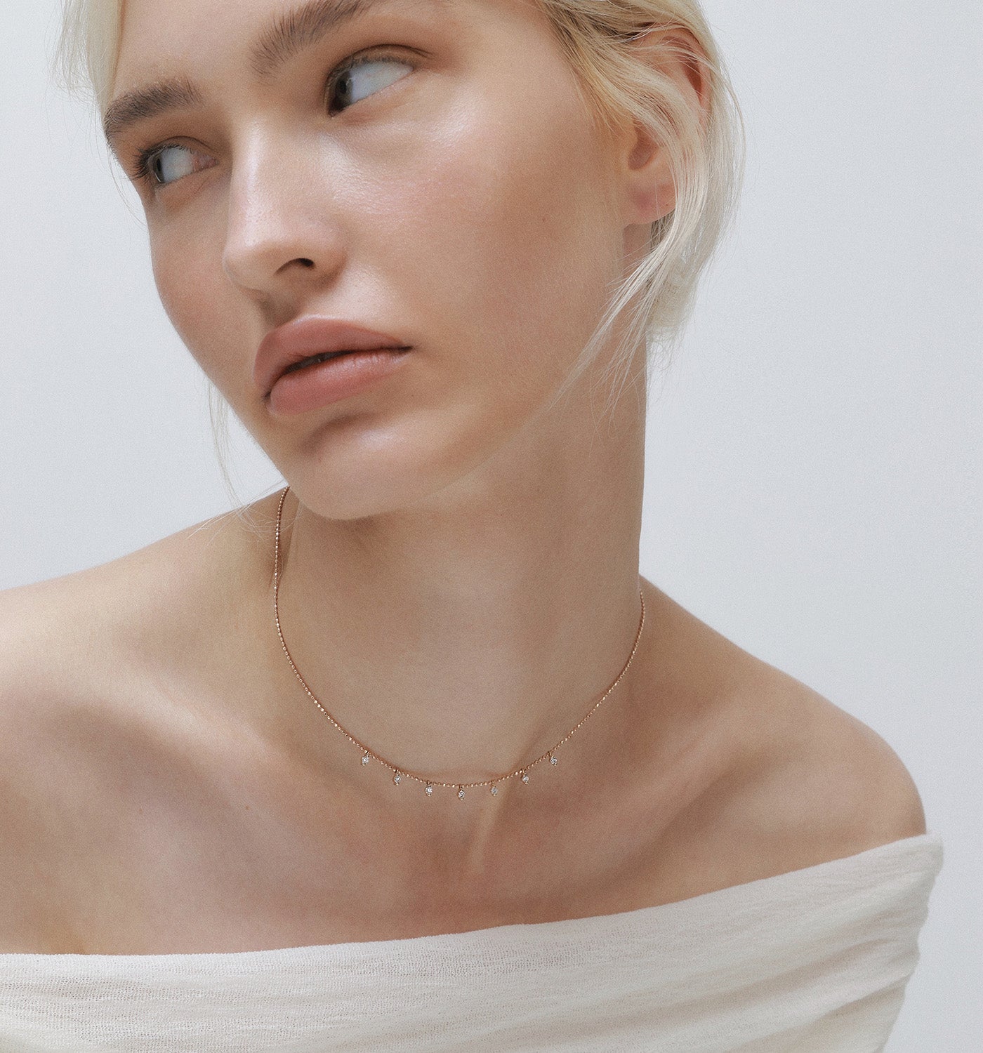 Flow necklace in rose gold set with seven natural diamonds worn on a model’s neck