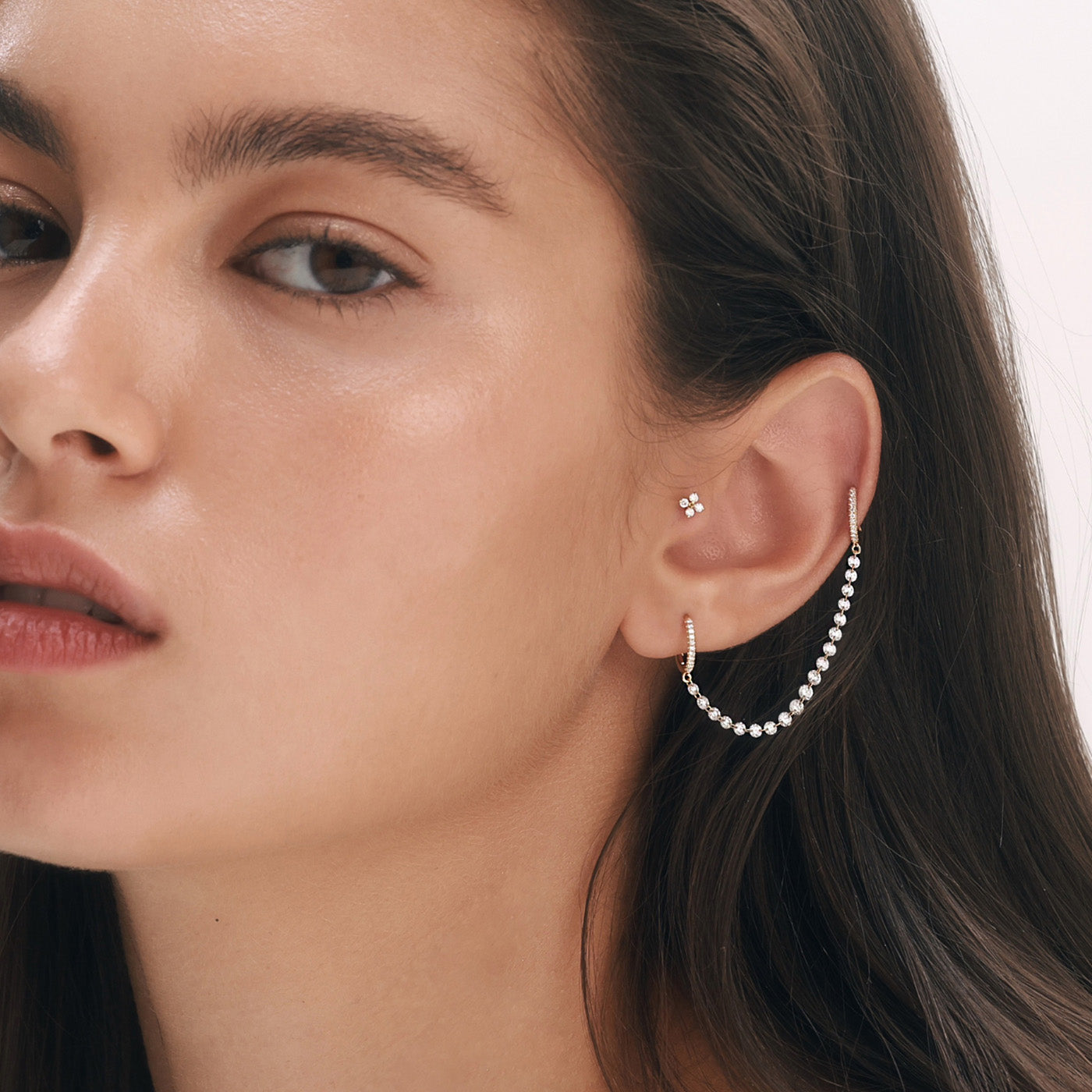 עגיל TWIN לשני חורים עם שרשרת Floating Diamonds של יהלומים טבעיים קדוחים מזהב ורוד, בשילוב עגיל FOUR Piercing Labret משובץ יהלומים, על דוגמנית.